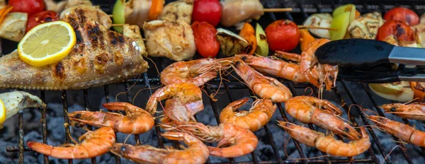 Shrimp, vegetables and fish are fried on a barbecue. Selective focus. Food.