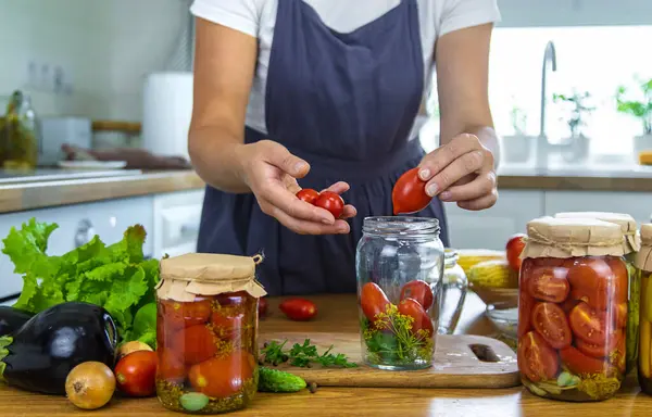 Woman canning vegetables in jars in the kitchen. Selective focus. Food.