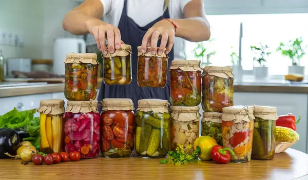 Woman canning vegetables in jars in the kitchen. Selective focus. Food.