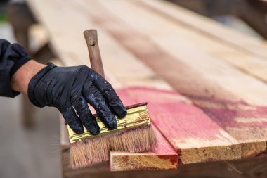 Bir adam tahtaya kırmızı bir antiseptik veriyor. Seçici odaklanma. Doğa.