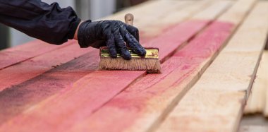 Bir adam tahtaya kırmızı bir antiseptik veriyor. Seçici odaklanma. Doğa.