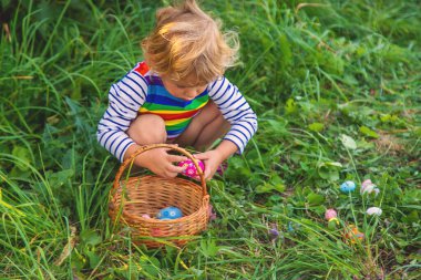 Bir çocuk çimenlerde paskalya yumurtası topluyor. Seçici odaklanma. Çocuk.