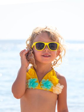 Deniz kabuğunu dinleyen bir çocuk. Seçici odaklanma. Doğa.