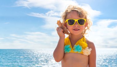 Deniz kabuğunu dinleyen bir çocuk. Seçici odaklanma. Doğa.