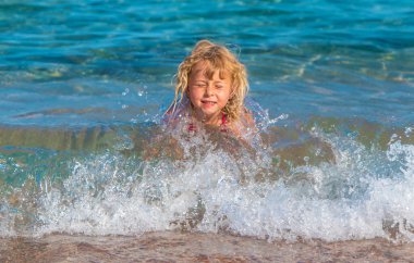 Bir çocuk denizde banyo yapar ve su sıçratır. Seçici odaklanma. Çocuk.