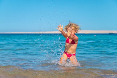 Bir çocuk denizde banyo yapar ve su sıçratır. Seçici odaklanma. Çocuk.