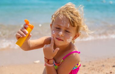 Çocuk yüz yüze güneş kremi sürüyor. Seçici odaklanma. çocuk.