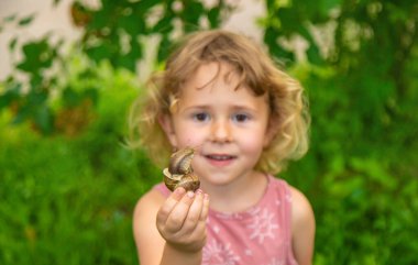 Elinde salyangoz tutan bir çocuk. Seçici odaklanma. Doğa.