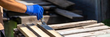 Bir adam bir tahtayı boyayla boyuyor. Seçici odaklanma. Doğa.