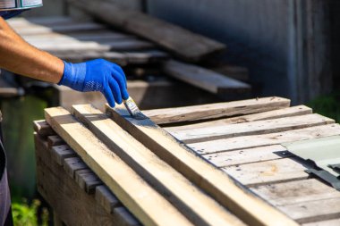 Bir adam bir tahtayı boyayla boyuyor. Seçici odaklanma. Doğa.