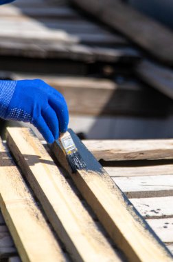 Bir adam bir tahtayı boyayla boyuyor. Seçici odaklanma. Doğa.