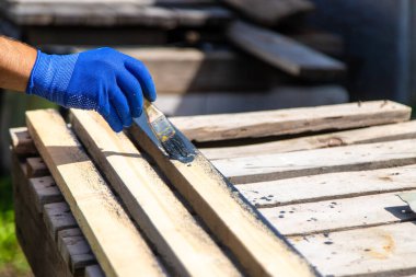 Bir adam bir tahtayı boyayla boyuyor. Seçici odaklanma. Doğa.