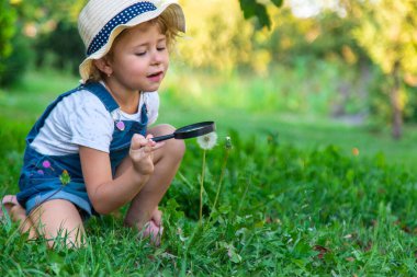 Bir çocuk doğadaki büyüteçten bakar. Seçici odaklanma. Çocuk,