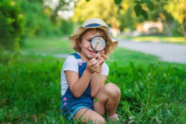 Bir çocuk doğadaki büyüteçten bakar. Seçici odaklanma. Çocuk,