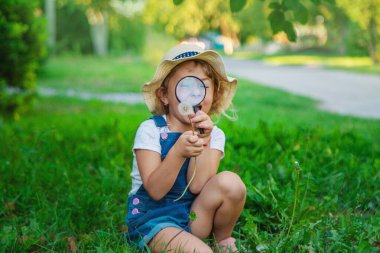 Bir çocuk doğadaki büyüteçten bakar. Seçici odaklanma. Çocuk,