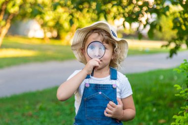 Bir çocuk doğadaki büyüteçten bakar. Seçici odaklanma. Çocuk,