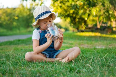 Bir çocuk doğadaki büyüteçten bakar. Seçici odaklanma. Çocuk,
