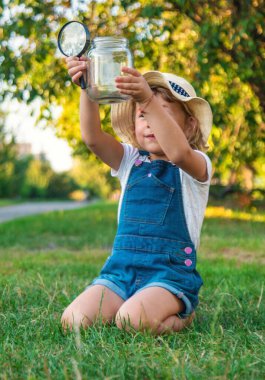 Bir çocuk doğadaki büyüteçten bakar. Seçici odaklanma. Çocuk,