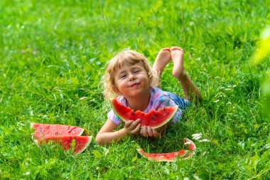 Çocuk yazın karpuz yiyor. Seçici odaklanma. Çocuk.
