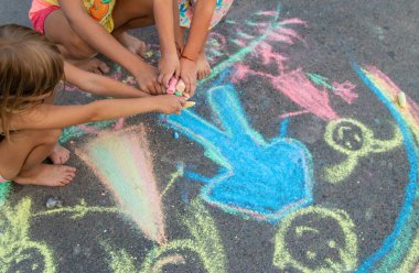 Çocuklar asfalta tebeşirle çizer. Seçici odaklanma. çocuk.