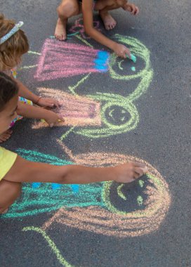 Çocuklar asfalta tebeşirle çizer. Seçici odaklanma. çocuk.