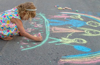 Çocuklar asfalta tebeşirle çizer. Seçici odaklanma. çocuk.