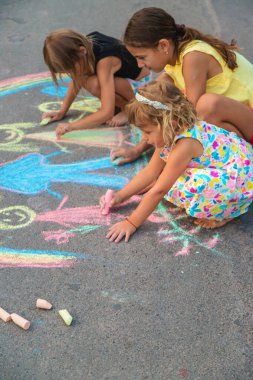 Çocuklar asfalta tebeşirle çizer. Seçici odaklanma. çocuk.