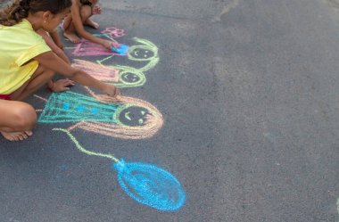 Çocuklar asfalta tebeşirle çizer. Seçici odaklanma. çocuk.