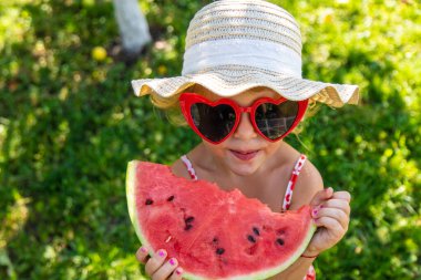 Bahçede karpuz yiyen bir çocuk. Seçici odaklanma. kız.