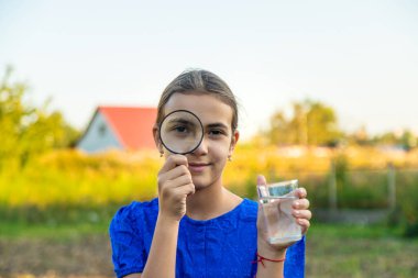Bir çocuk büyüteçle suya bakar. Seçici odaklanma. çocuk.