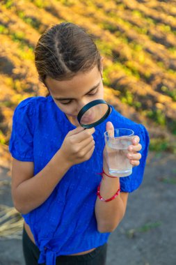 Bir çocuk büyüteçle suya bakar. Seçici odaklanma. çocuk.