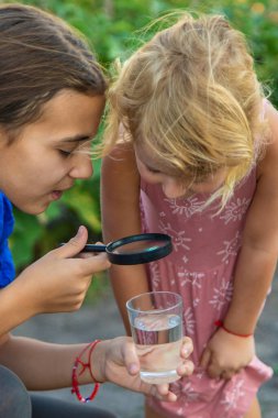 Bir çocuk büyüteçle suya bakar. Seçici odaklanma. çocuk.