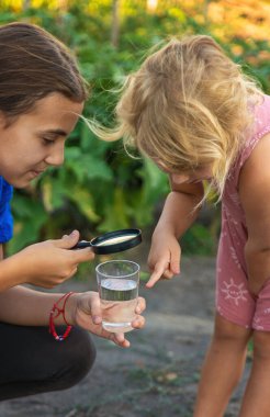 Bir çocuk büyüteçle suya bakar. Seçici odaklanma. çocuk.