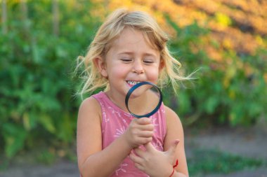Bir çocuk doğadaki büyüteçten bakar. Seçici odaklanma. Çocuk.
