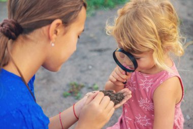 Bir çocuk büyüteçle toprağa bakar. Seçici odaklanma. Çocuk.