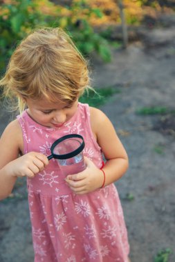Bir çocuk büyüteçle suya bakar. Seçici odaklanma. çocuk.