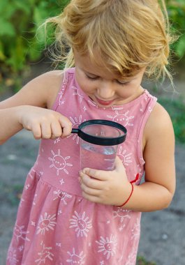 Bir çocuk büyüteçle suya bakar. Seçici odaklanma. çocuk.