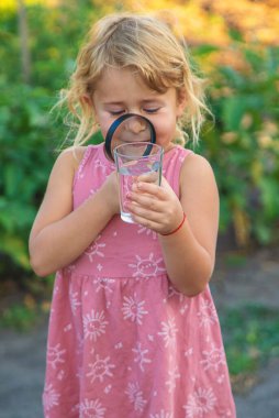 Bir çocuk büyüteçle suya bakar. Seçici odaklanma. çocuk.