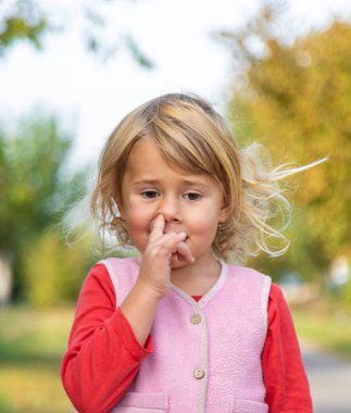 Bir çocuk parmağıyla burnunu karıştırıyor. Seçici odaklanma. çocuk.