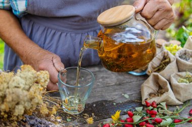 Şifalı bitkiler ve çay içen yaşlı kadın. Seçici odaklanma. Doğa.