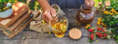 Şifalı bitkiler ve çay içen yaşlı kadın. Seçici odaklanma. Doğa.