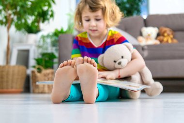 Evde oyuncak ayıyla kitap okuyan bir çocuk var. Seçici odaklanma. çocuk.