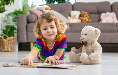 Evde oyuncak ayıyla kitap okuyan bir çocuk var. Seçici odaklanma. çocuk.