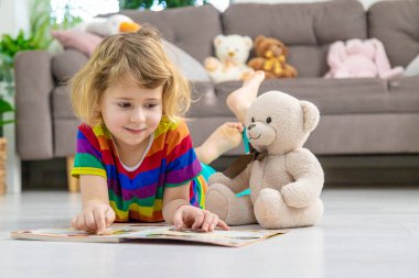 Evde oyuncak ayıyla kitap okuyan bir çocuk var. Seçici odaklanma. çocuk.