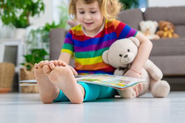 Evde oyuncak ayıyla kitap okuyan bir çocuk var. Seçici odaklanma. çocuk.