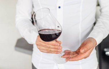 Ellerinde bir kadeh kırmızı şarap. Seçici odaklanma. iç.