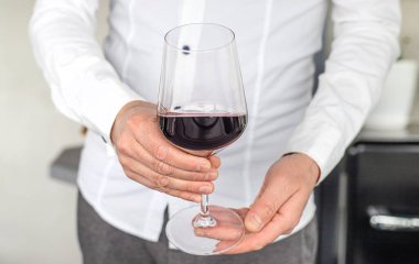 Ellerinde bir kadeh kırmızı şarap. Seçici odaklanma. iç.