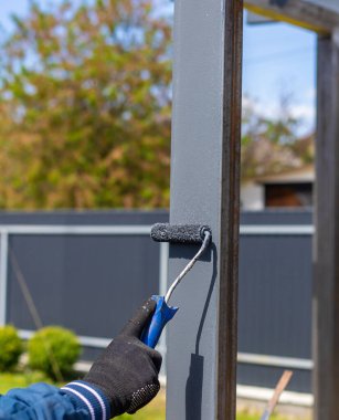Metal direkleri boyayan adam. Seçici odaklanma. Doğa.