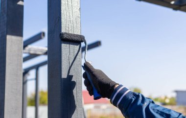 Tahta direkleri boyayan bir adam. Seçici odak.