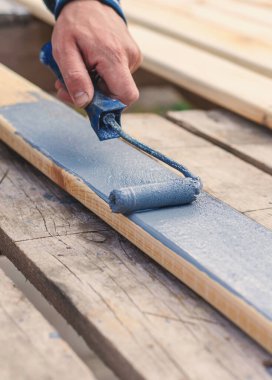 Bir adam bir tahtayı boyayla boyuyor. Seçici odaklanma. İnsanlar.